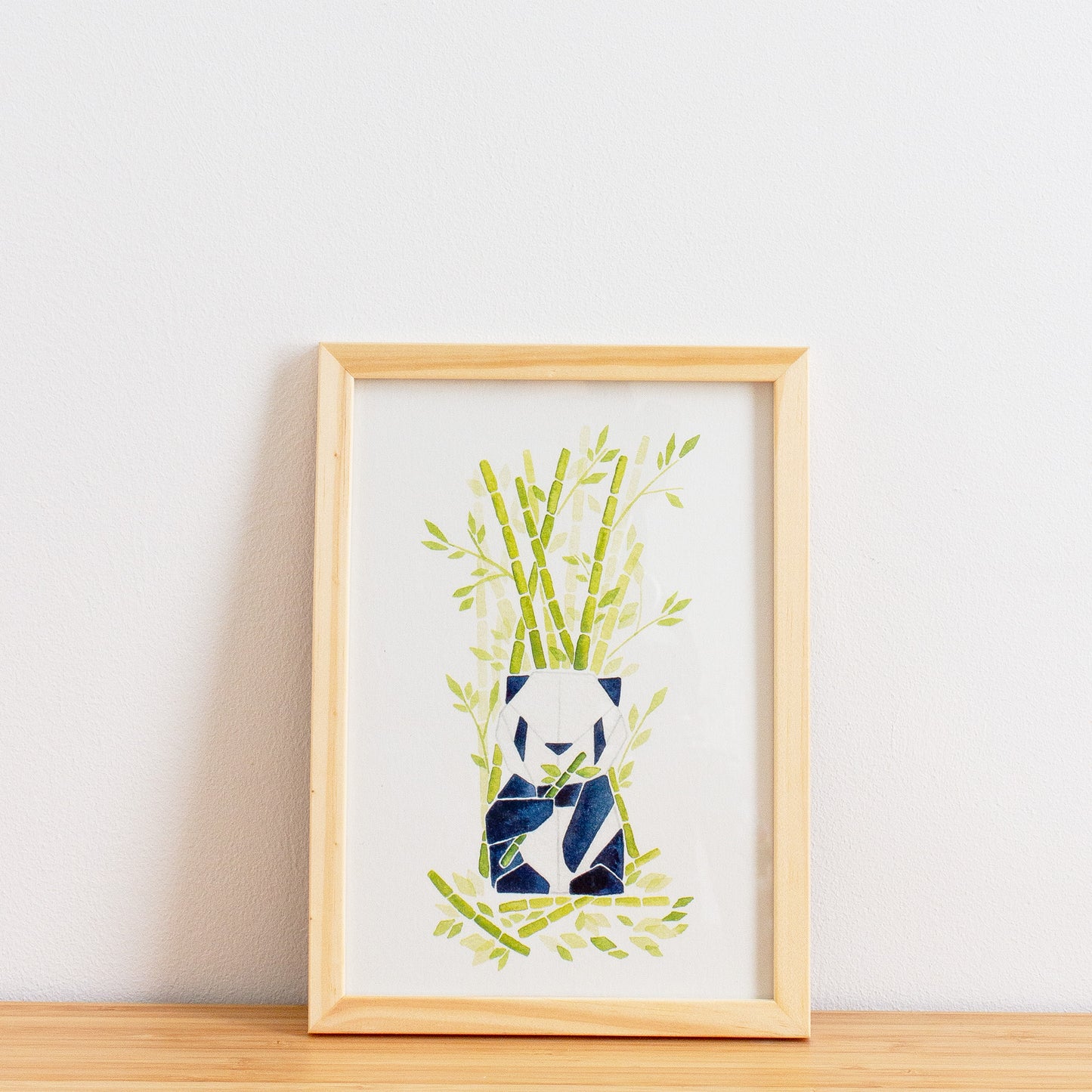 Watercolour painting art print. The watercolour illustration shows an origami panda sitting among bamboo trees, branches and leaves.