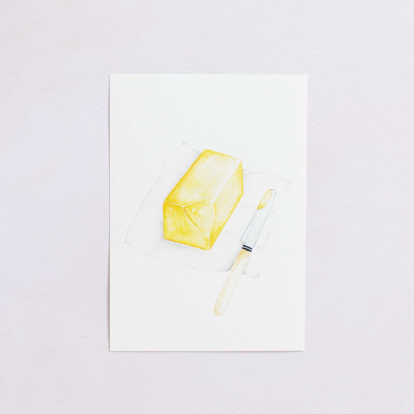 Watercolour colour art print. This watercolour illustration shows a block of butter on paper with a butter knife on the side.