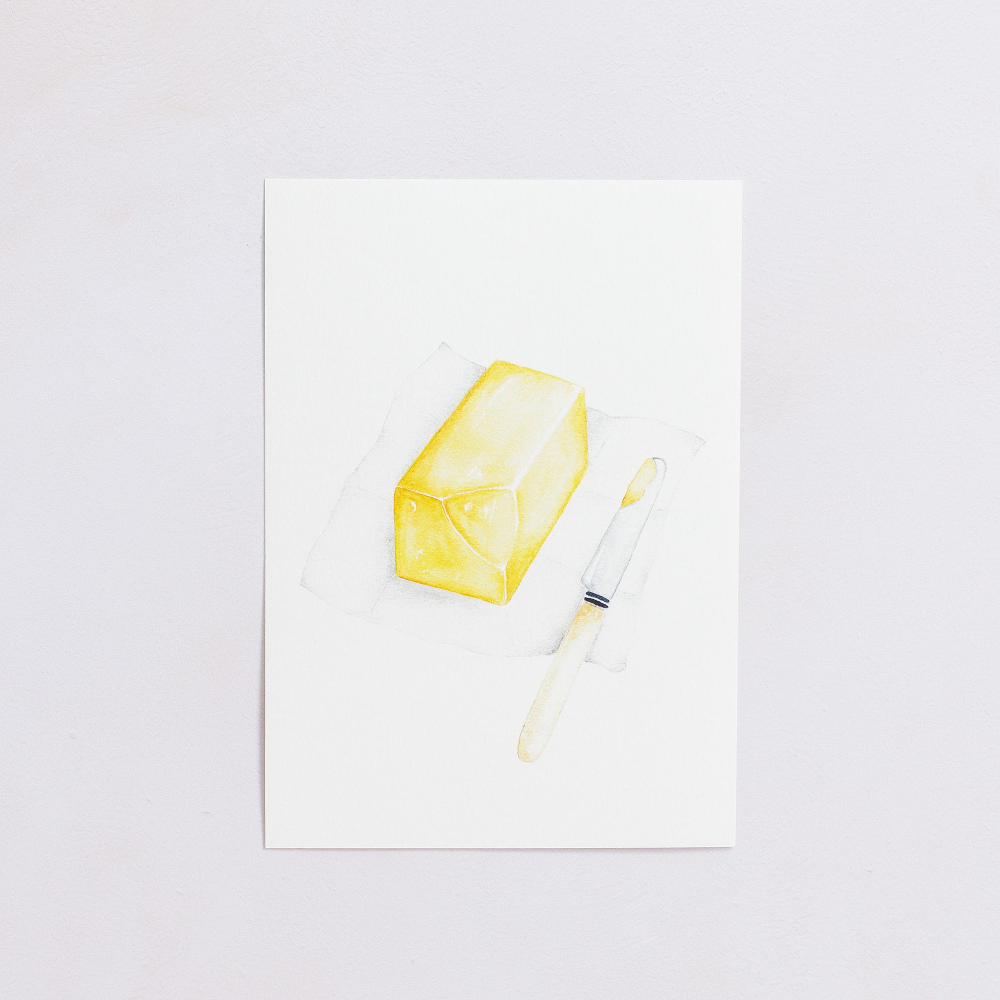 Watercolour colour art print. This watercolour illustration shows a block of butter on paper with a butter knife on the side.