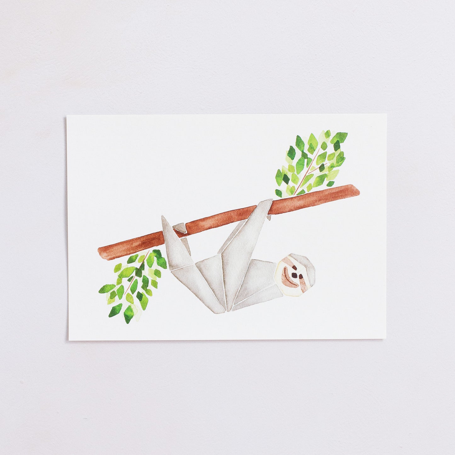 Watercolour painting art print. The watercolour illustration shows an origami sloth hanging from a tree branch with leaves.