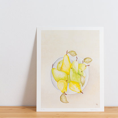 Image is a photo of a Limited edition art print sitting on bamboo wood surface with white background. The print is a reproduction from a handmade watercolour painting representing pears in a grey white bowl from above.