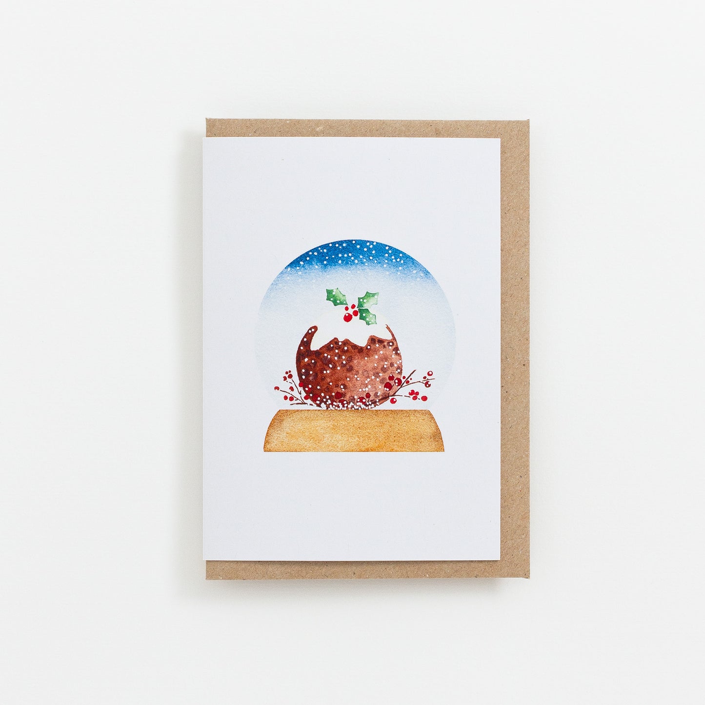 A festive food Snow Globe card designed from handmade watercolour painting. The illustration is a round Christmas pudding topped with icing and holly.