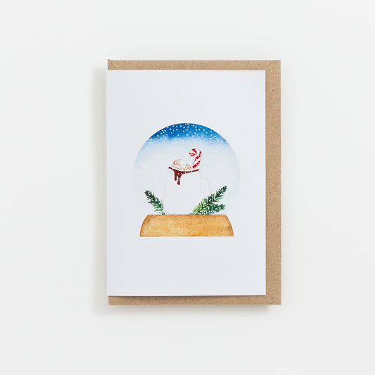 A festive food Snow Globe card designed from handmade watercolour painting. The illustration is a festive hot chocolate topped with marshmallow, cocoa powder and a candy cane.